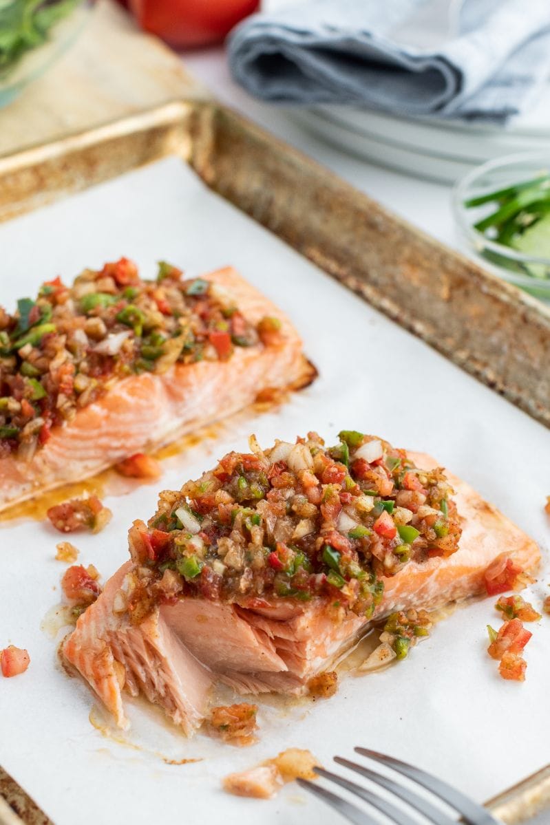 flaking away cooked salmon on baking sheet