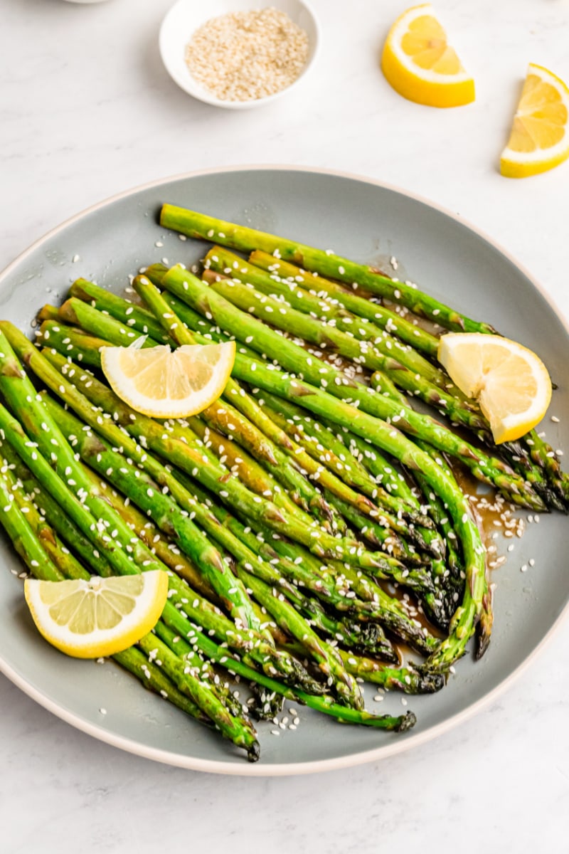 plate of asparagus with lemon wedges