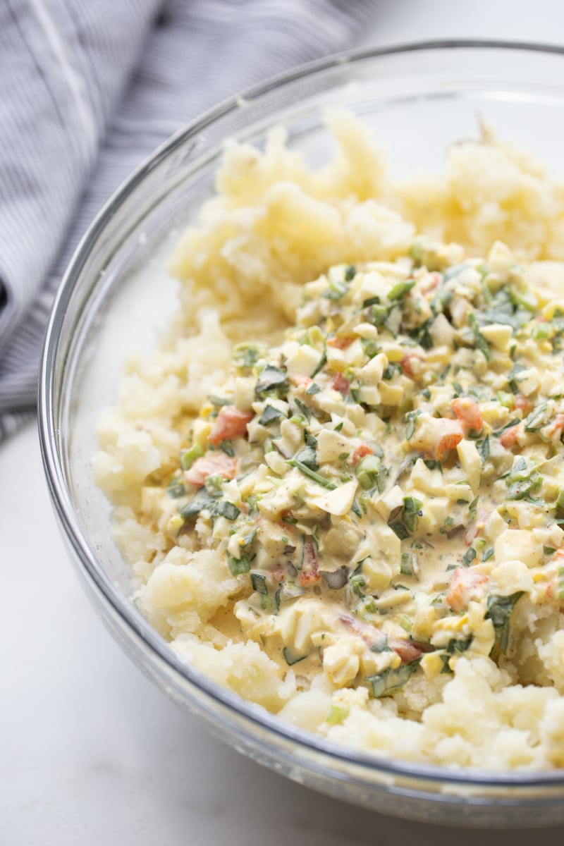 ingredients in glass bowl for potato salad ready to be tossed