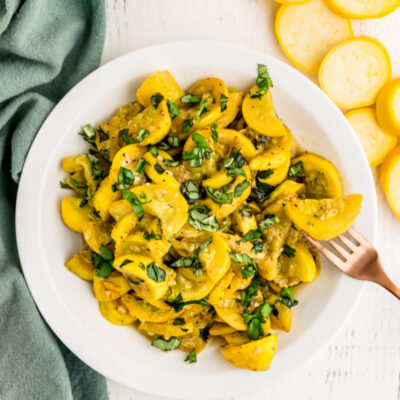 smothered yellow squash and basil in a white dish