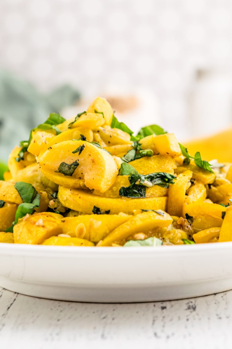 cooked squash and basil on a white plate