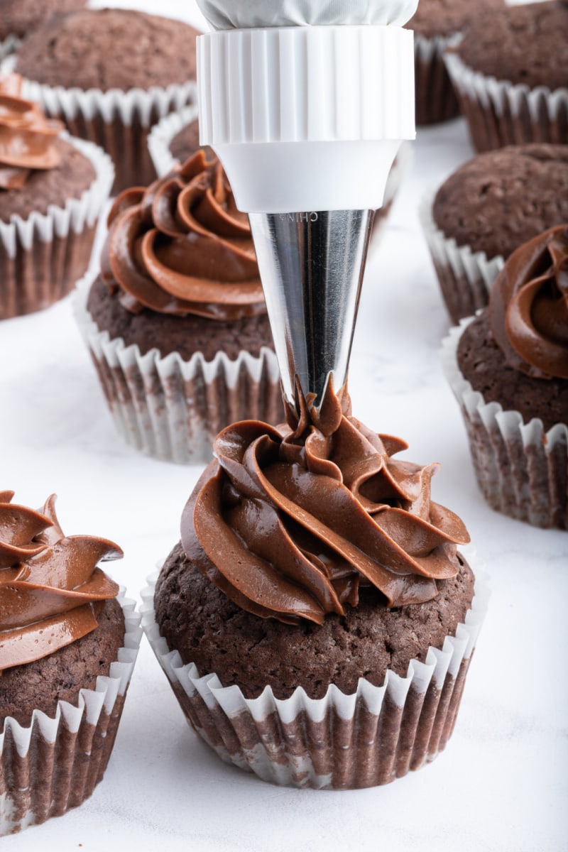 piping frosting onto chocolate cupcake