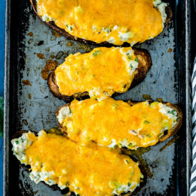 overhead shot of four tuna melts on a baking sheet set on a blue and white striped towel