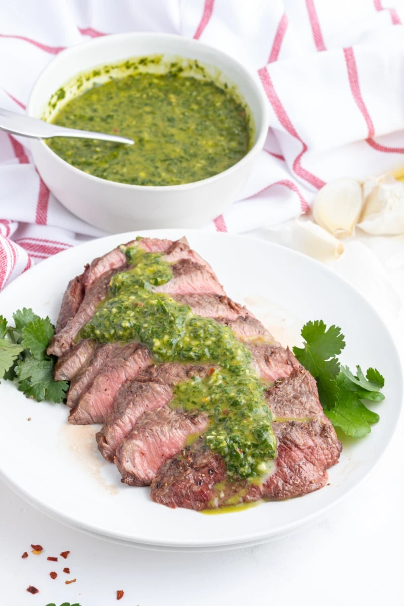 sliced steak with chimichurri sauce on top