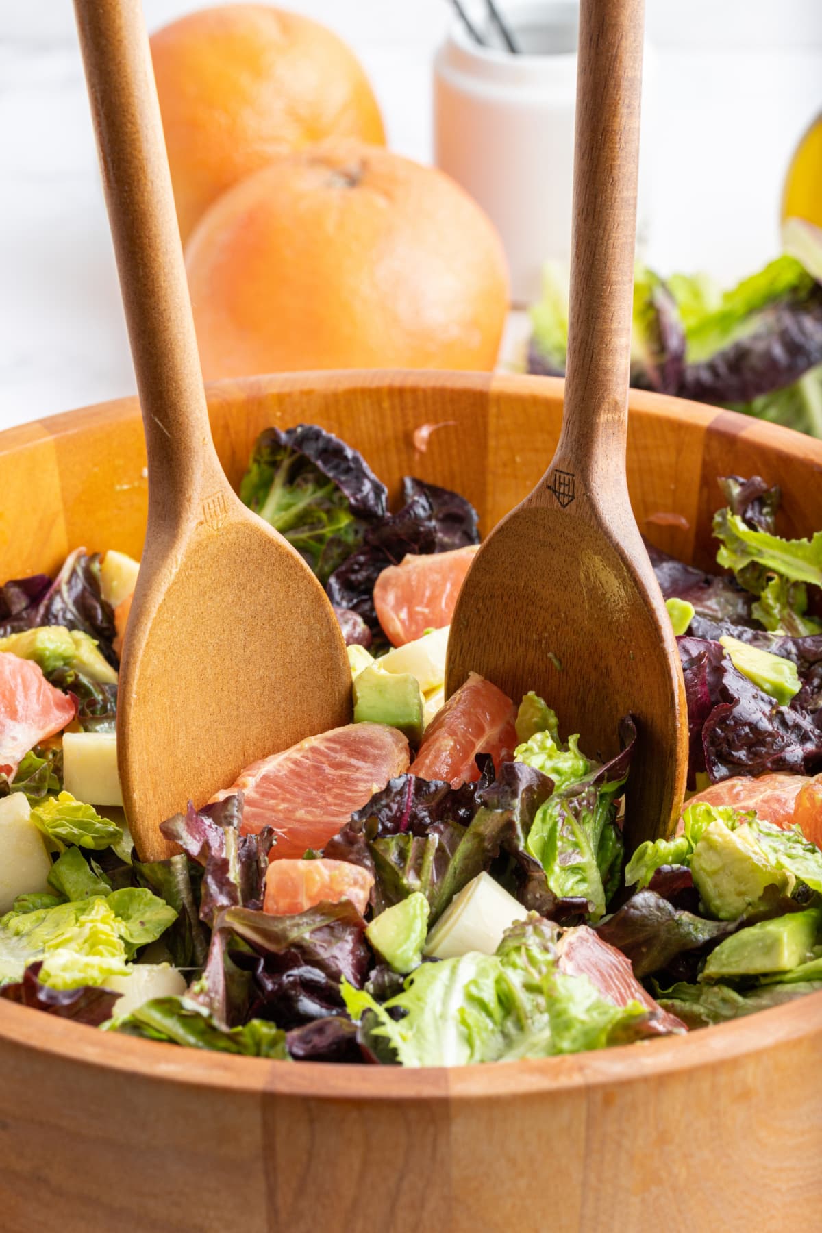 wooden salad servers serving salad out of wooden bowl