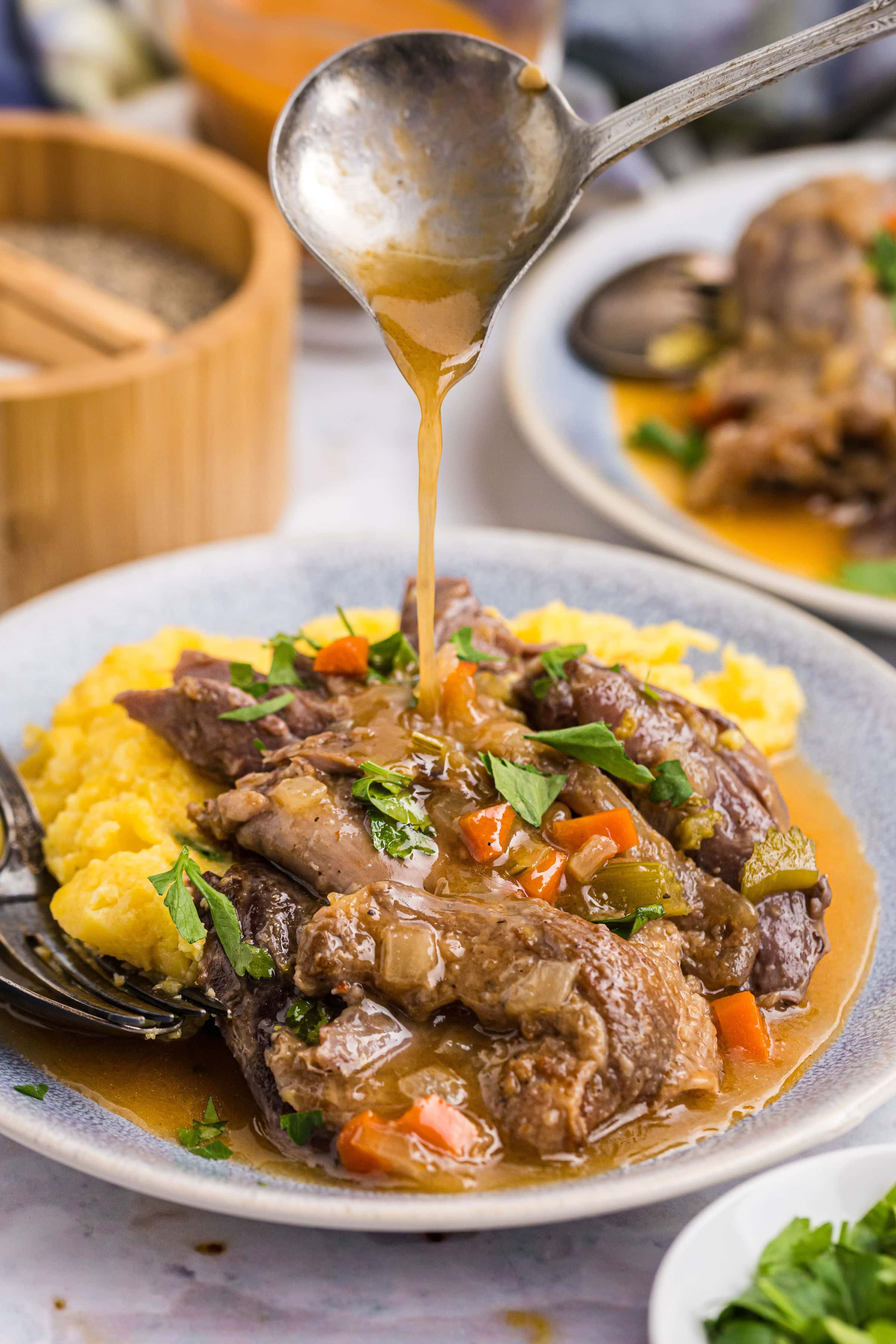 Lamb Osso Buco recipe from RecipeGirl.com : traditional Osso Bucco is made with veal, but this version is made with lamb shanks. pouring gravy over plating of lamb osso buco