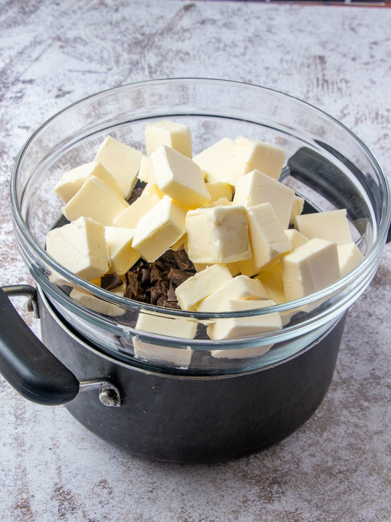 showing a pot with a glass bowl placed on top of it. Bowl is filled with butter and chocolate chips.