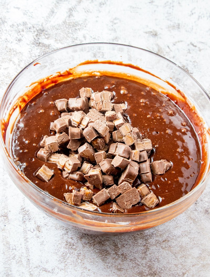 brownie batter in a glass bowl with chopped milky way candy bars added in