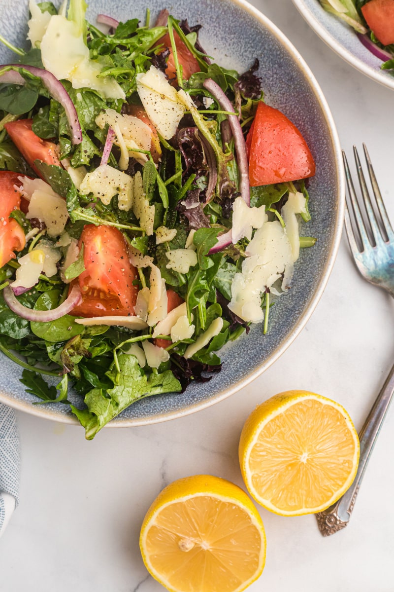 mixed green salad with honey lemon dressing in bowl with lemons on side