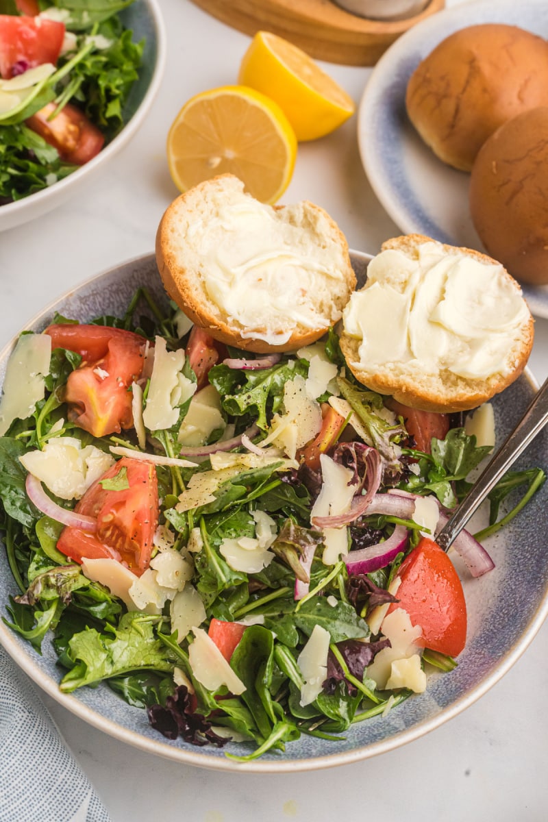 mixed green salad with honey lemon dressing in bowl with two pieces of bread