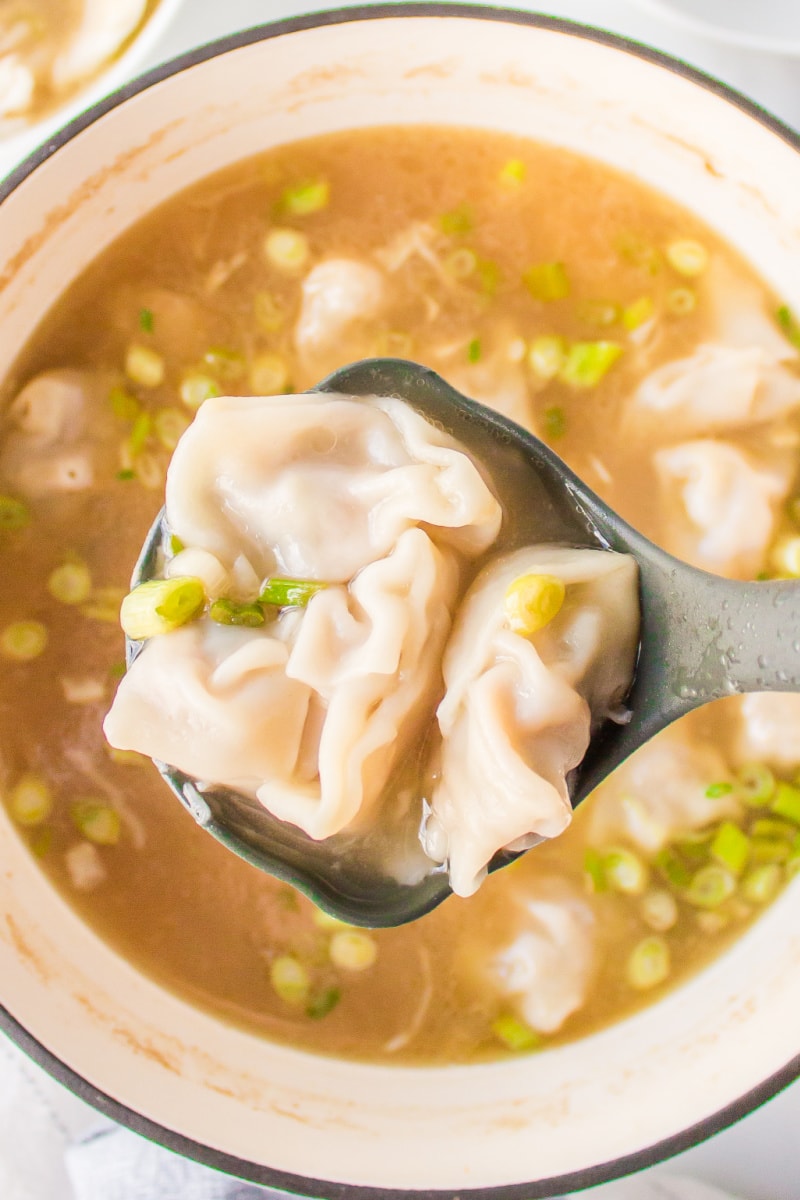 ladle full of wontons above pot of wonton soup