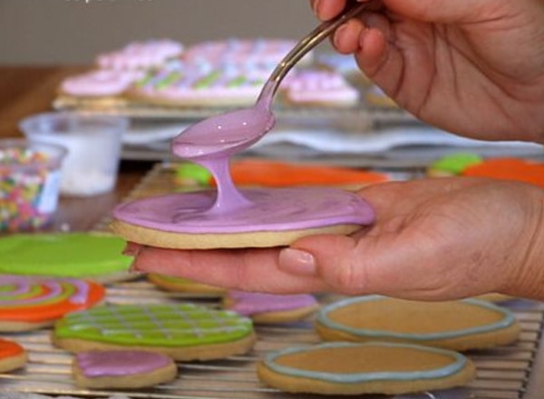 spooning royal icing onto sugar cookies