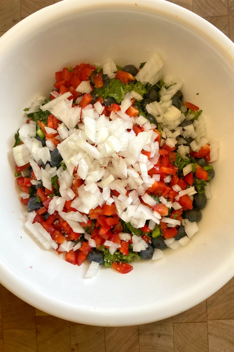ingredients stacked in a white bowl to make blueberry salsa