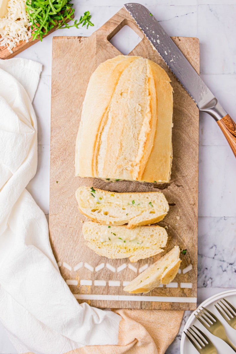 loaf of cheese and herb bread on cutting board with pieces sliced