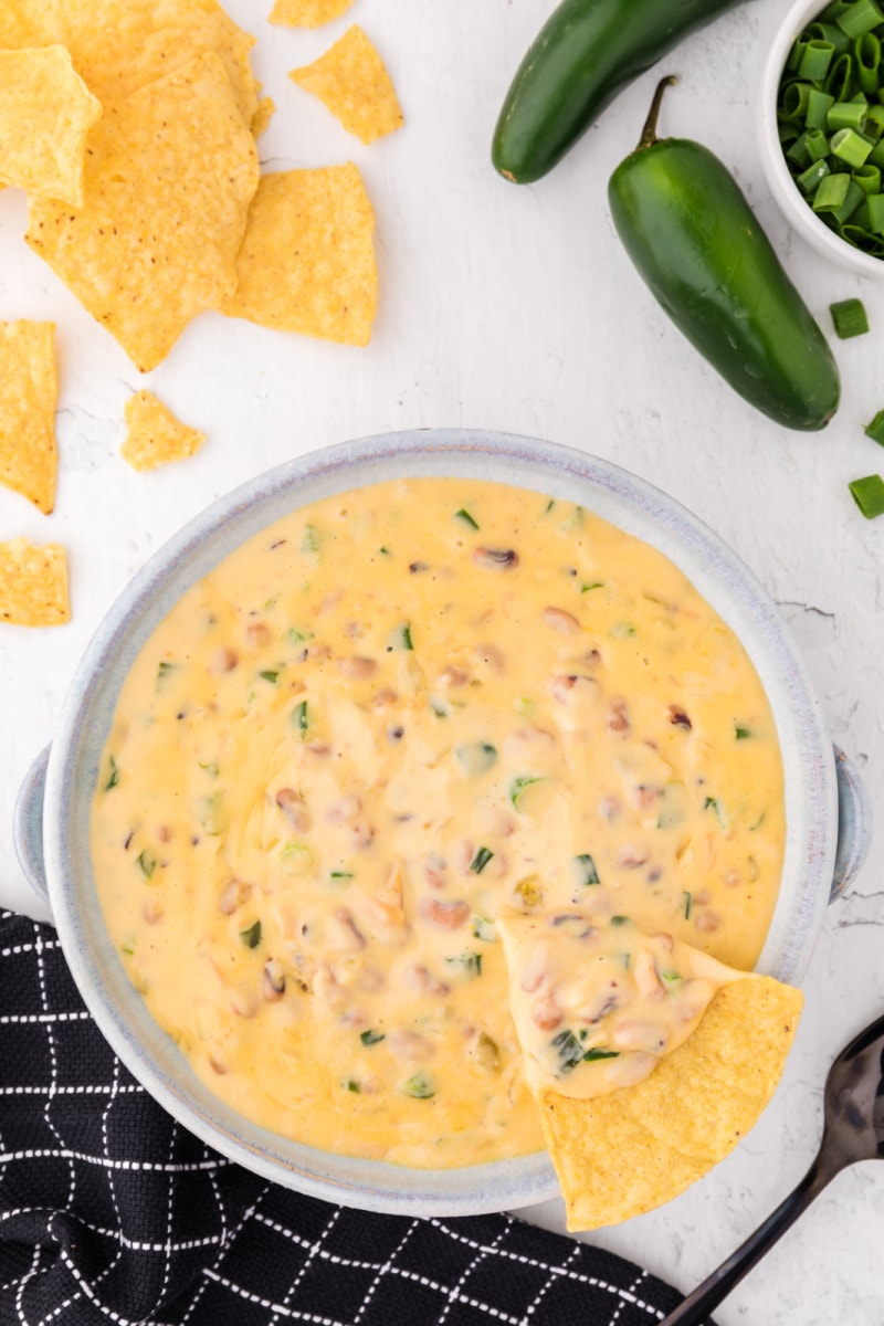 cheesy black eyed pea dip in a bowl with a chip dunked in