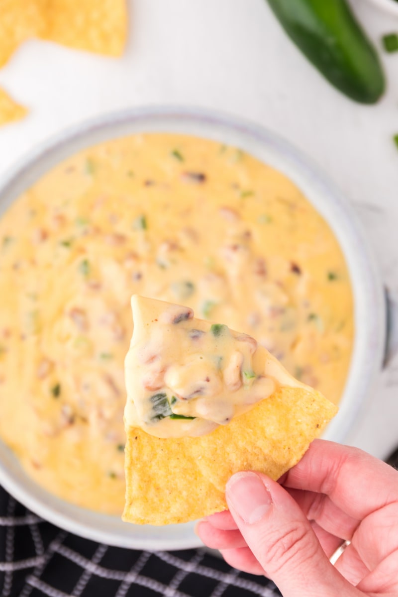 hand holding chip that has been dipped in cheesy black eyed pea dip