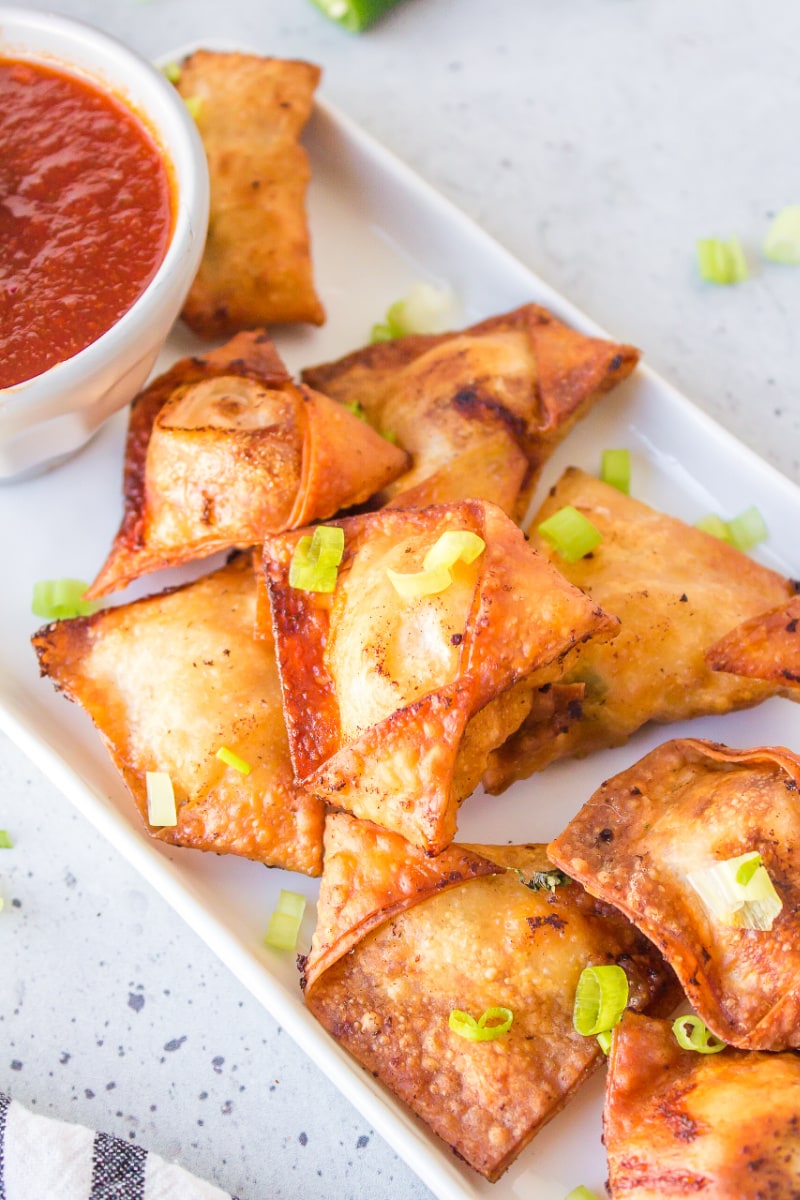 chicken and shrimp won tons on a plate with a bowl of sauce