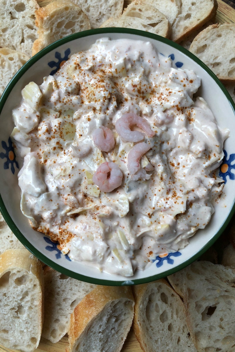 overhead shot of bowl of Chili Shrimp Dip surrounded by baguette slices