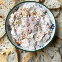 Overhead shot of a bowl of chili shrimp dip surrounded by baguette slices