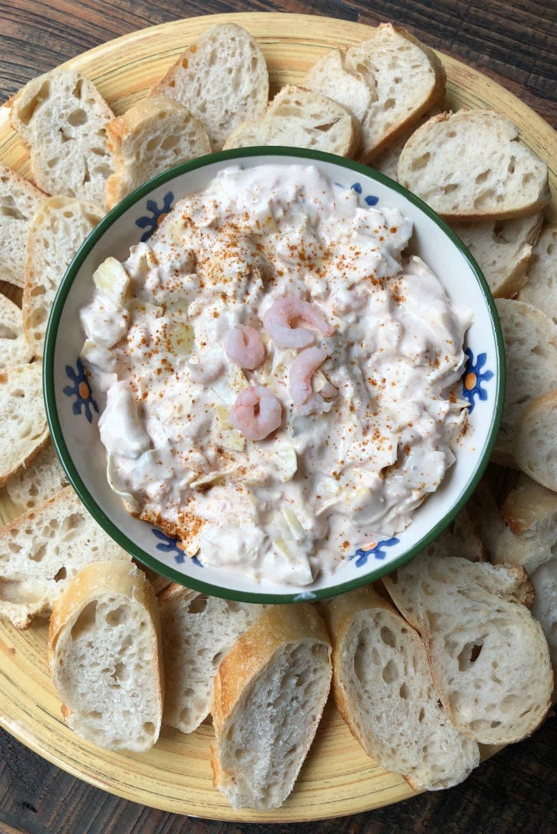 overhead shot of a Bowl of Chili Shrimp Dip on a round platter with baguette slices