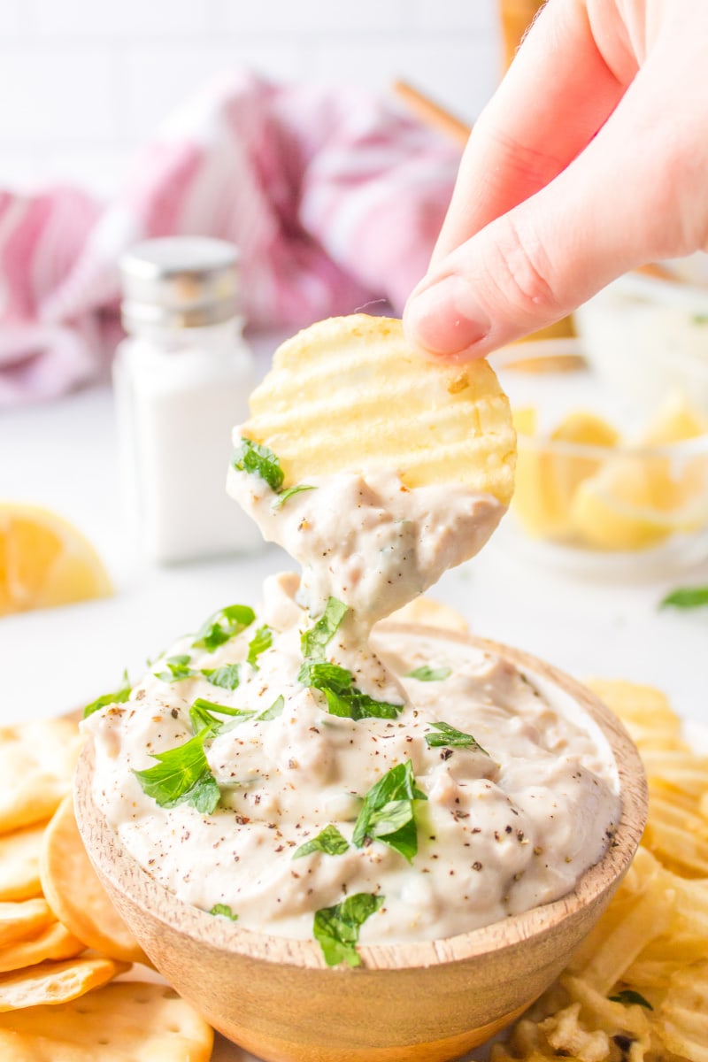 hand dipping chip into clam dip