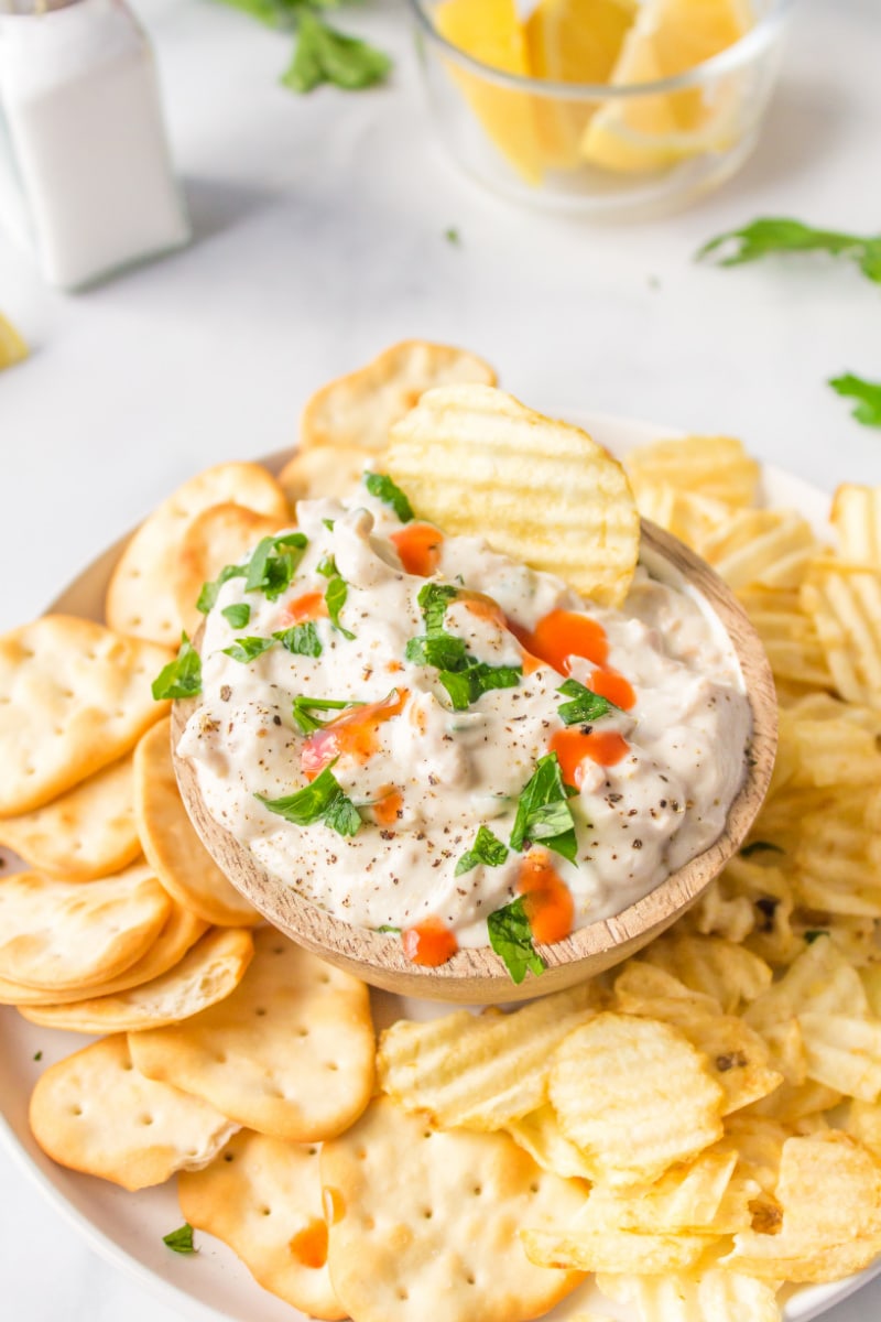 clam dip in dish with chips with tabasco drizzled on top