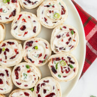 cranberry feta pinwheels on a white platter set on red plaid napkin