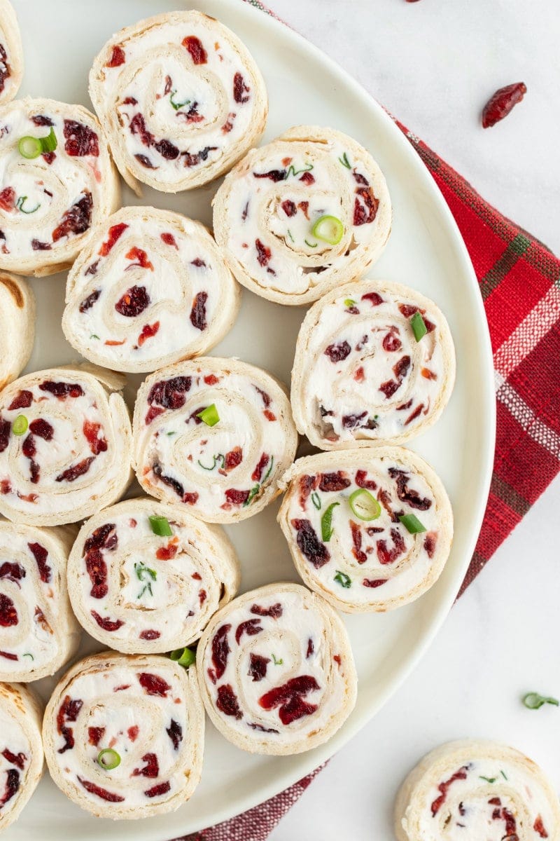 cranberry feta pinwheels on a white platter set on red plaid napkin