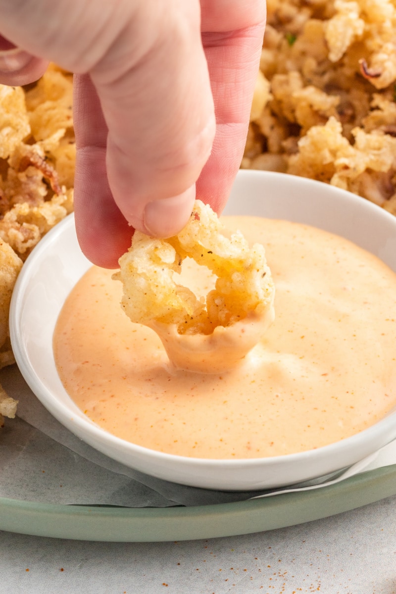 dipping a piece of fried calamari into dipping sauce