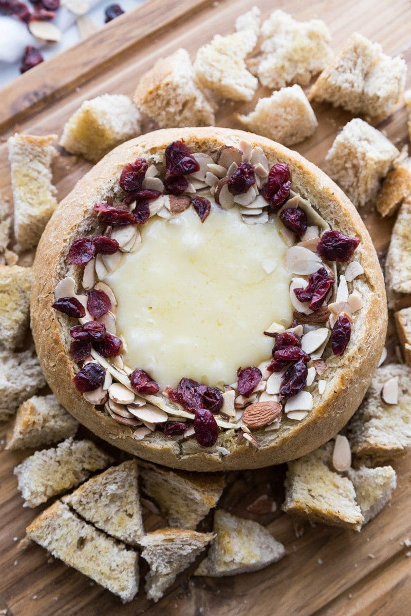 Baked Brie in a bread bowl with sliced almonds and dried cranberries