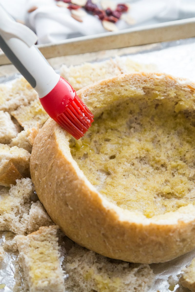 adding garlic butter to bread bowl