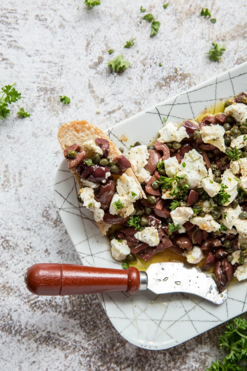 olive and goat cheese appetizer with a spreader