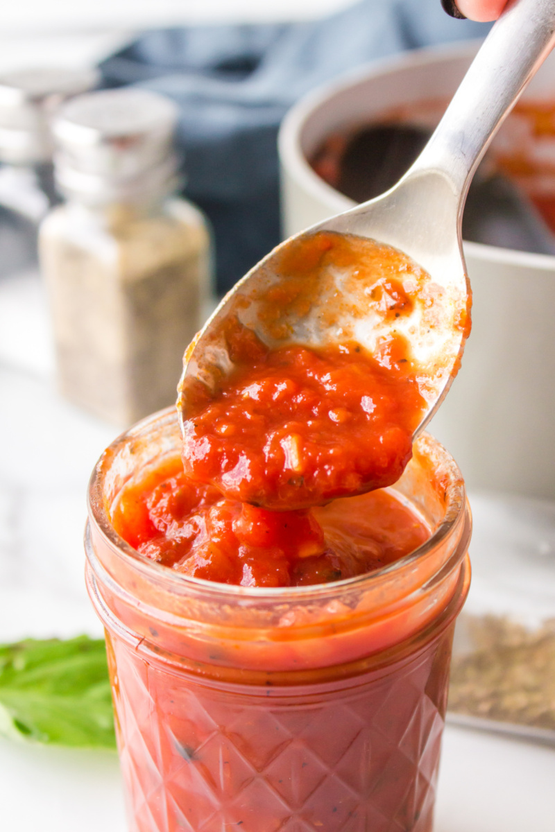 spoon taking pizza sauce out of jar