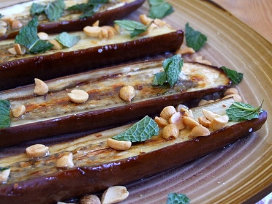 roasted eggplant on a plate with chiles peanuts and mint