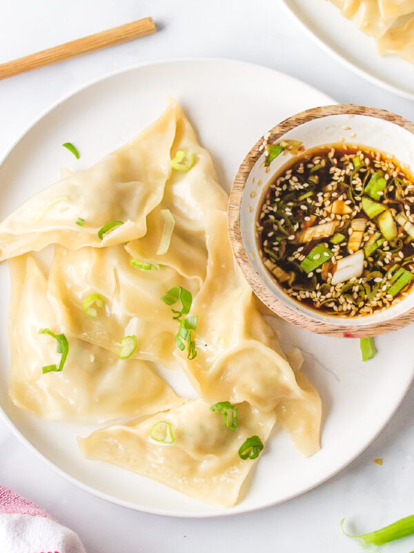 steamed shrimp dumplings on a plat with a bowl of dipping sauce