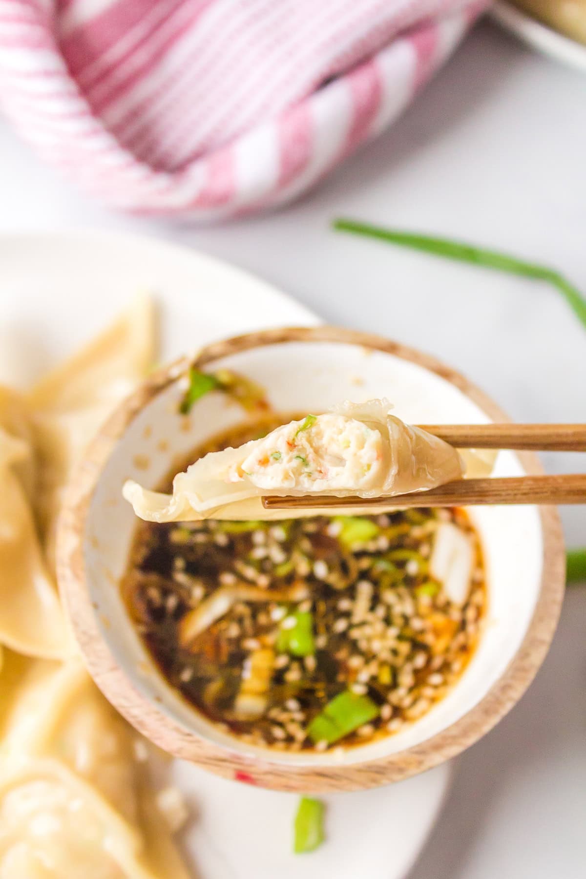 Steamed Shrimp Dumplings recipe from RecipeGirl.com : Asian dumplings with sesame dipping sauce : Weight Watchers chopsticks holding dumpling that has bite taken out