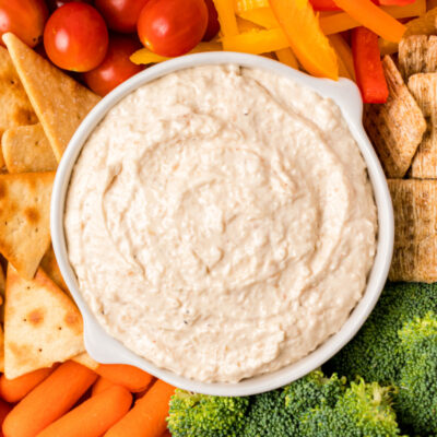 bowl of sweet caramelized onion spread surrounded by veggies and crackers