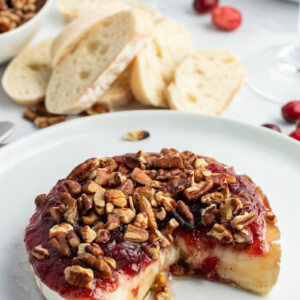 cranberry baked brie displayed with a wedge taken out of it
