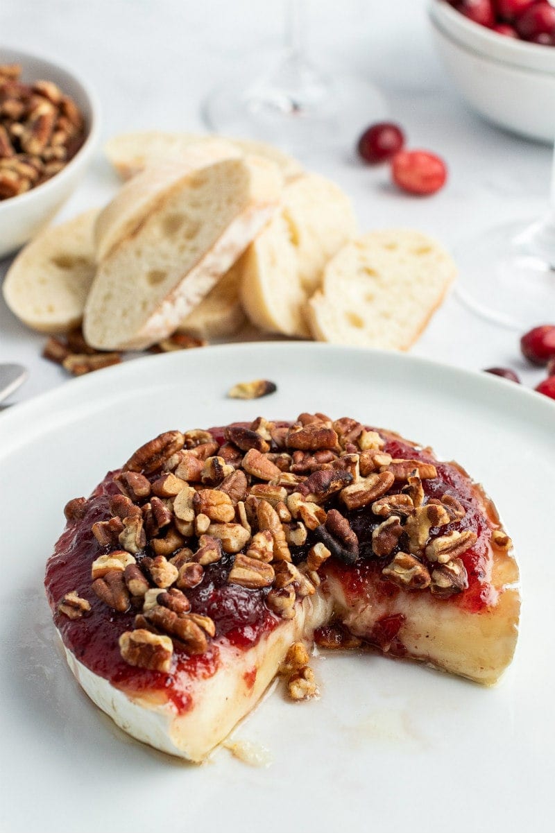 cranberry baked brie displayed with a wedge taken out of it