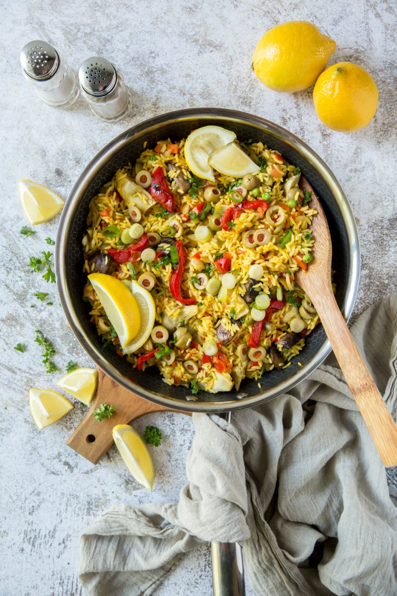 pan of vegetable paella with wooden spoon