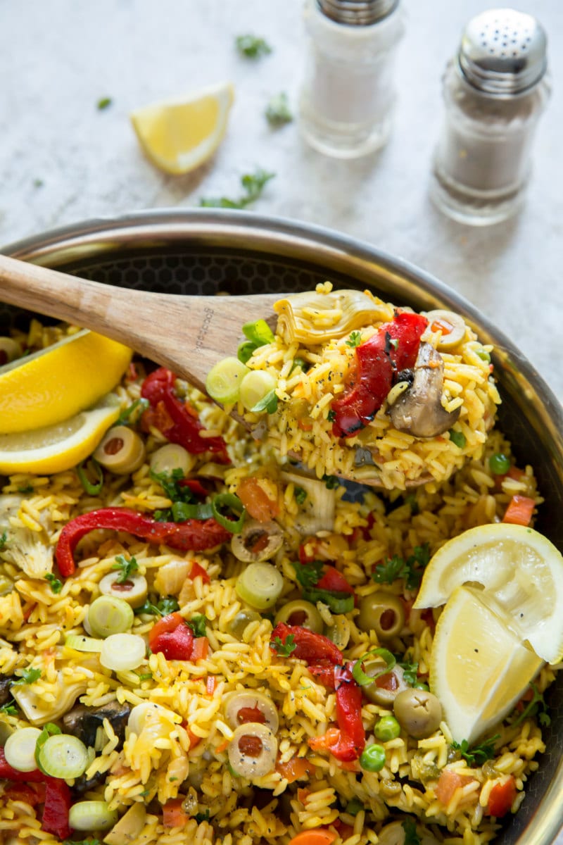 Spooning out vegetable paella out of pan