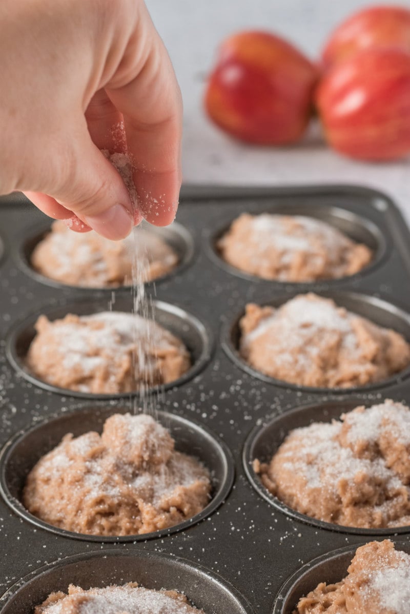 sprinkling sugar on muffin batter in muffin pan