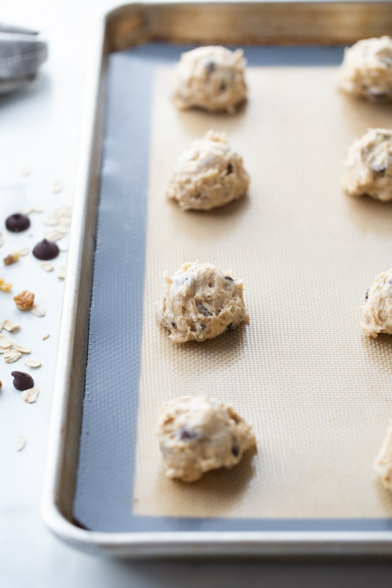 banana walnut chocolate chip cookies in blobs on a baking sheet ready for the oven