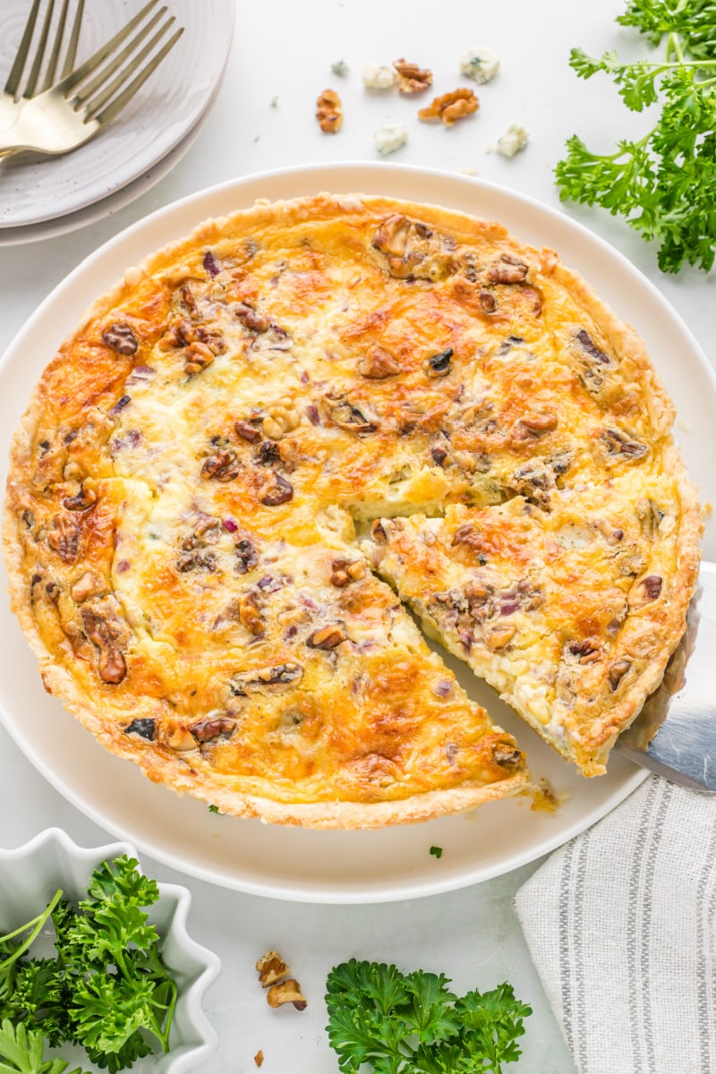 spatula taking out a slice of blue cheese and walnut quiche