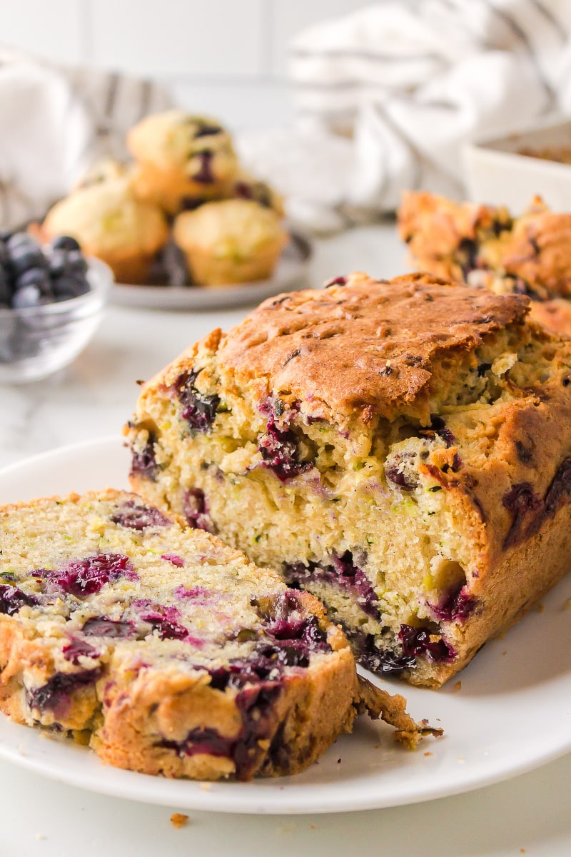 loaf of blueberry zucchini bread on plate sliced open