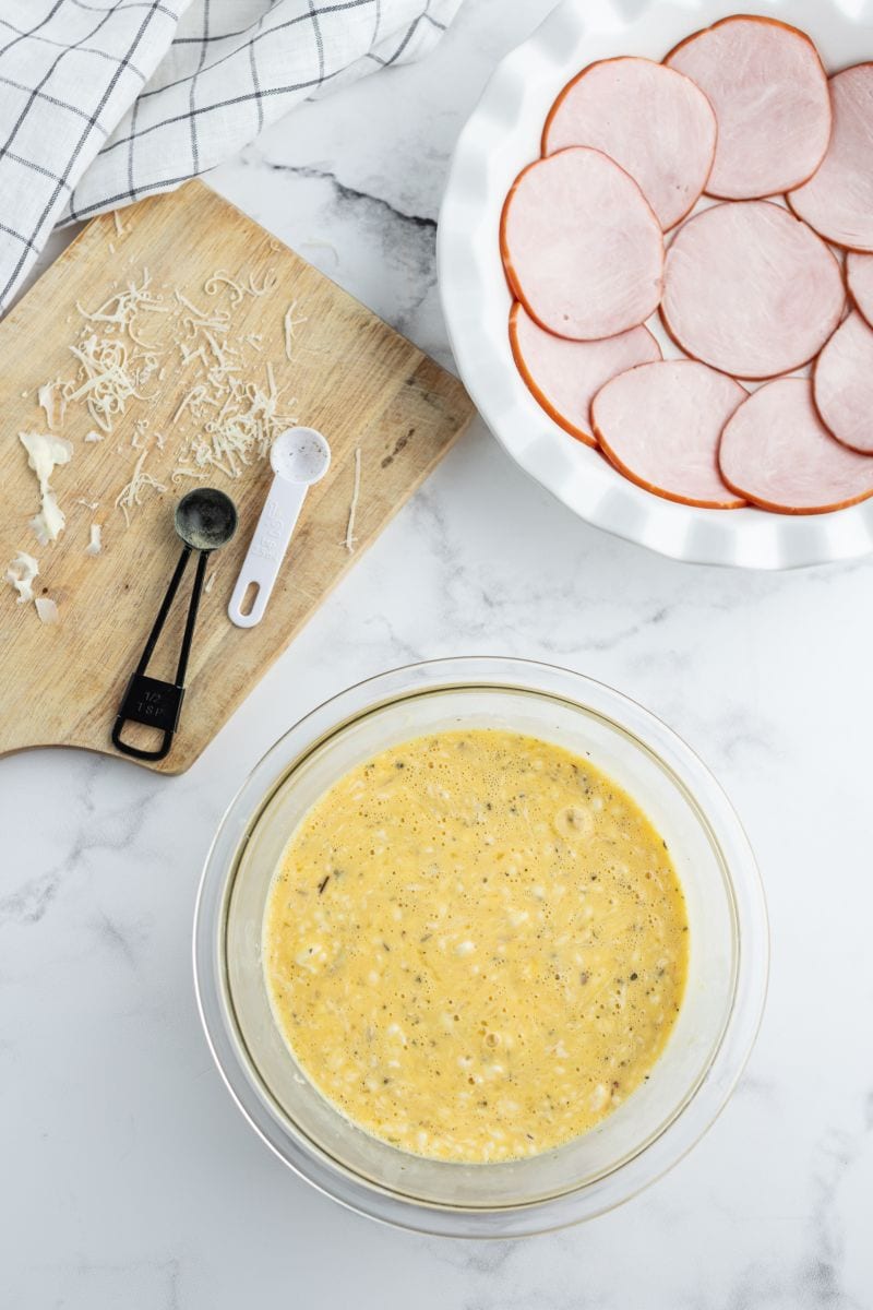 showing process of making quiche with bacon lined plate and egg mixture in bowl