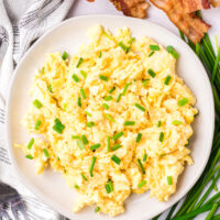 scrambled eggs on a plate with chives on top