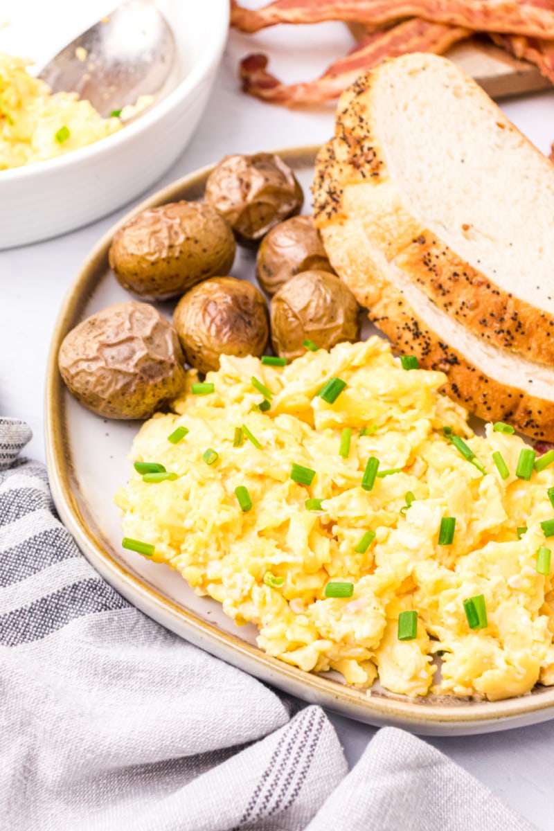 creamy scrambled eggs on a plate with potatoes and toast