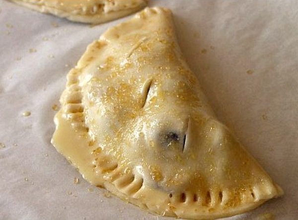 showing how to make cherry turnovers adding egg wash to the turnover before baking