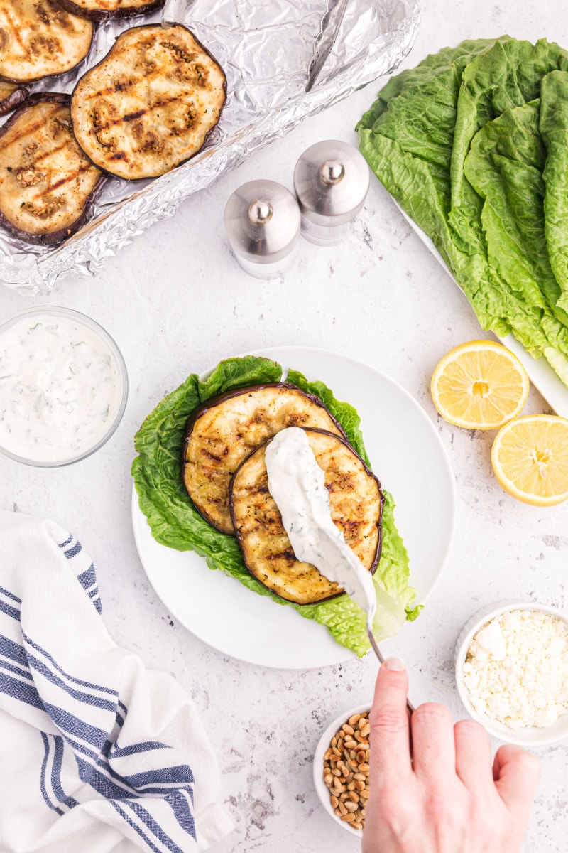 spooning dressing onto grilled eggplant